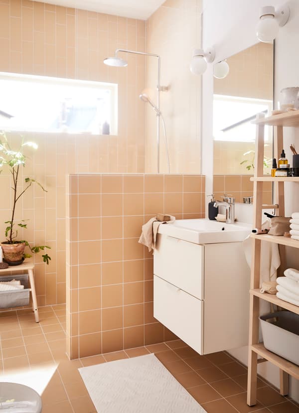 La série de pommeaux de douche chromés avec fonction jet concentré IKEA BROGRUND et la série de rangement en bouleau VILTO dans une petite salle de bain de style spa.