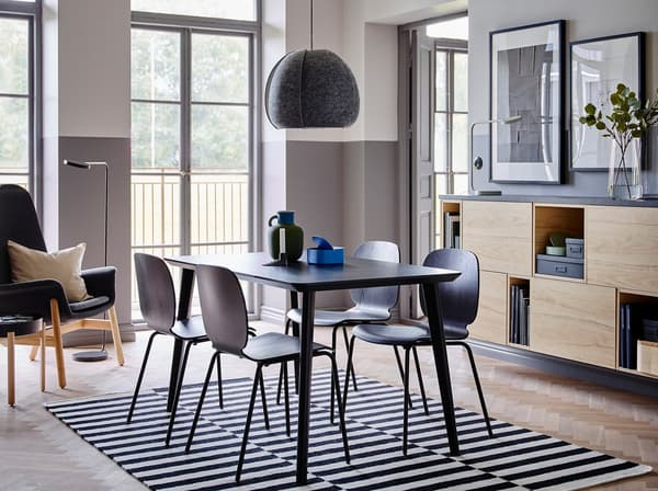 La table LISABO facile à monter et les chaises SVENBERTIL en noir constituent une combinaison élégante au centre d’une pièce aux murs moitié blancs, moitié gris, meublée de rangements ouverts et fermés en frêne.