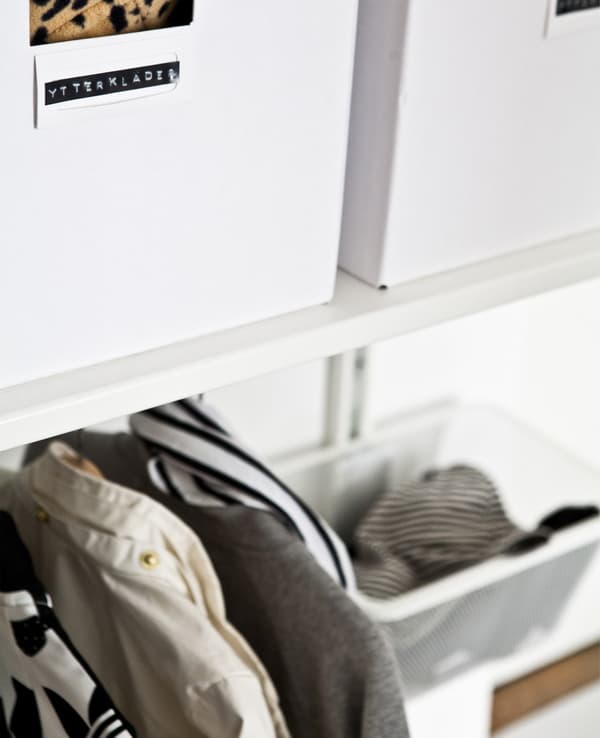 Labelled white boxes on a shelf above a hanging rail.