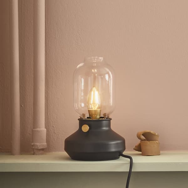 Lampe de table semblable à une lampe à pétrole, sur une étagère.