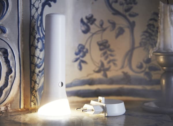 Lampe torche allumée et chargeur posé à côté.