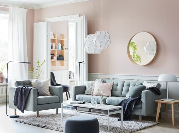 LANDSKRONA light green sofa sectional, SJÖPENNA pendant lamps and black YPPERLIG standing lamps in a pink walledl living room.