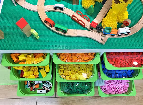 Large green containers filled with lego inside a storage unit.