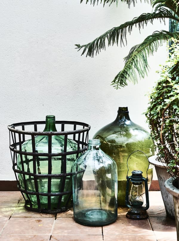 Large green glass vases and pots on a balcony.