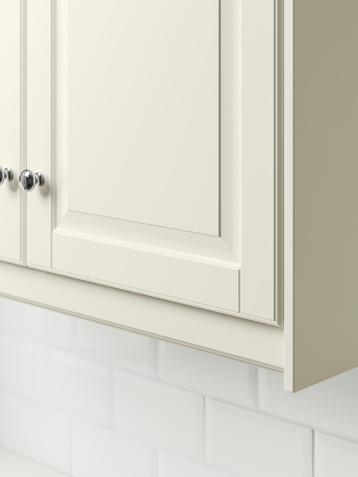 Le coin inférieur d’une armoire blanc cassé avec son bandeau-décor blanc cassé.