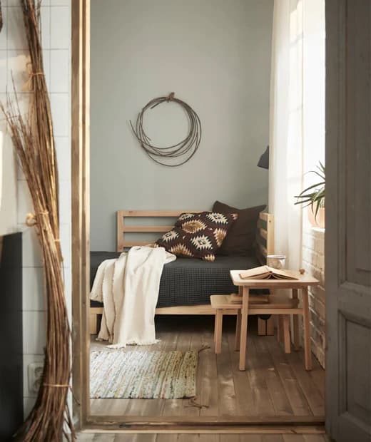 Le linge de lit de couleur neutre ajouté au lit d’appoint TARVA en bois naturel habillent joliment cette pièce multifonction, et le petit tapis assure le confort des pieds.