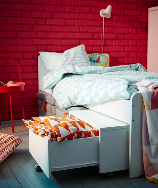 Le lit et le rangement sur roulettes SLÄKT conviennent très bien aux petites pièces. Le rangement reçoit oreiller et draps, et il est facile à sortir de sous le lit. Les matelas pliants SLÄKT s’insèrent parfaitement sous le lit.