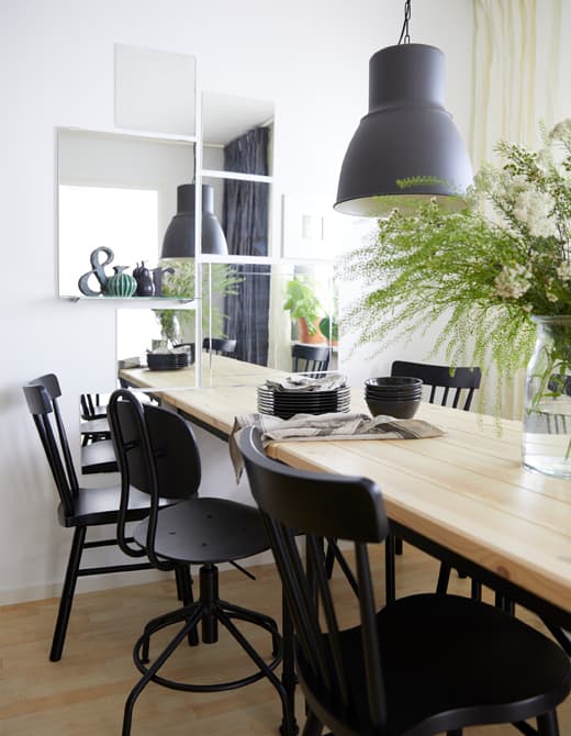 Le mur de la salle à manger est décoré de plusieurs miroirs rectangulaires et carrés placés à côté de la table.