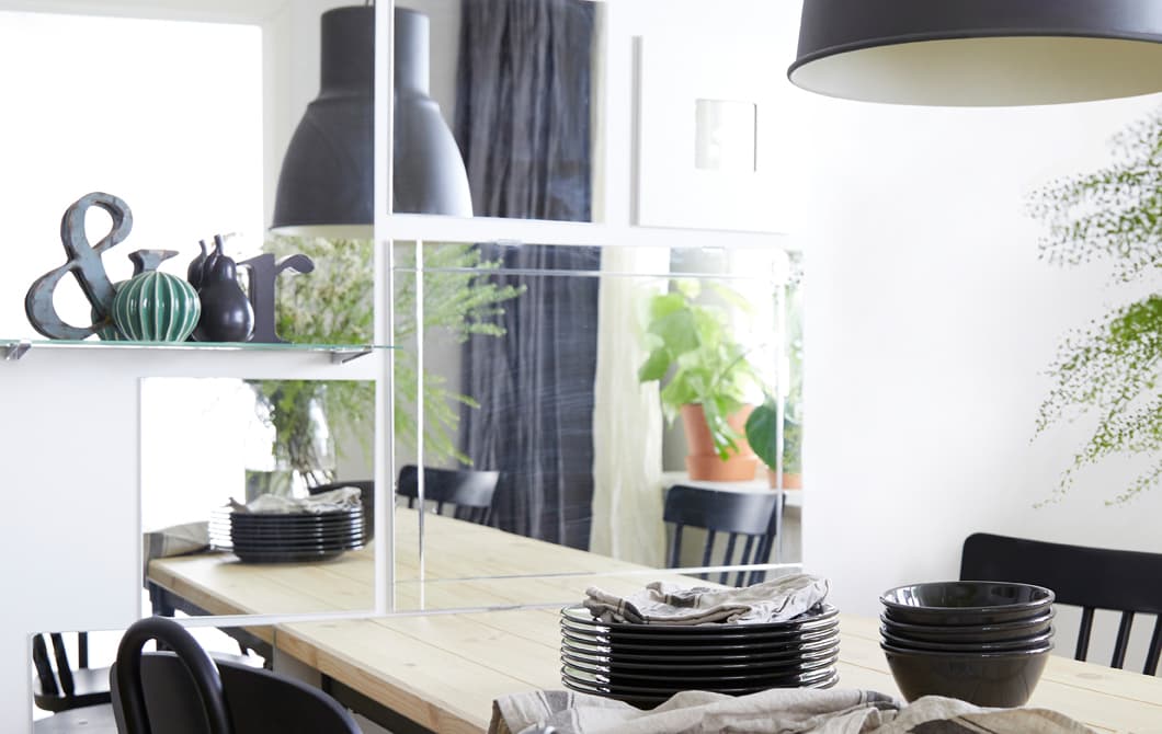 Le mur de la salle à manger est décoré de plusieurs miroirs rectangulaires et carrés placés à côté de la table.