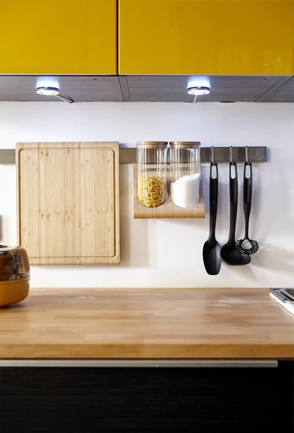 Les supports muraux de cette cuisine permettent de ranger les ustensiles et outils de cuisine au-dessus du plan de travail.
