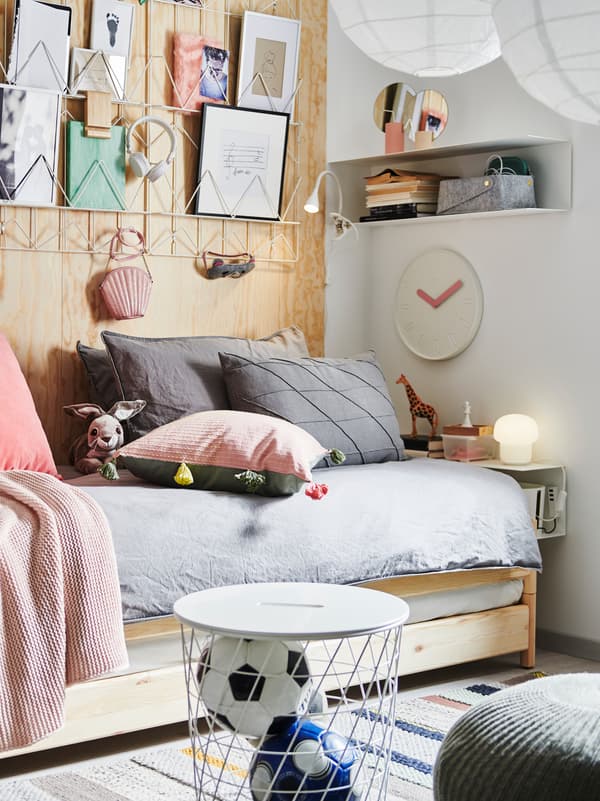 Letto impilabile UTÅKER con tanti cuscini, immagini incorniciate, scaffale da parete BOTKYRKA, tavolino/contenitore e decorazioni.