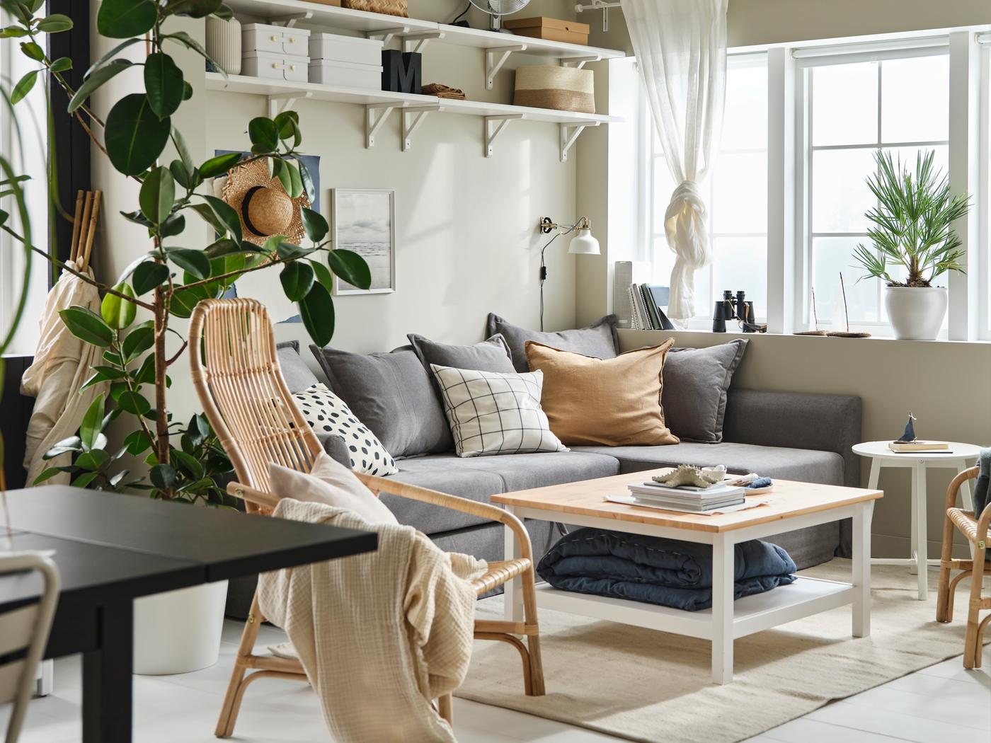 Lichte, heldere woonkamer met grote ramen, een HOLMSUND hoekslaapbank en een HEMNES salontafel, opgeluisterd met textiel en grote planten.