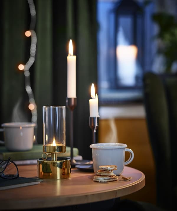 Light blue EGENDOM mug in a durable enameled steel on a table set with three lit candles