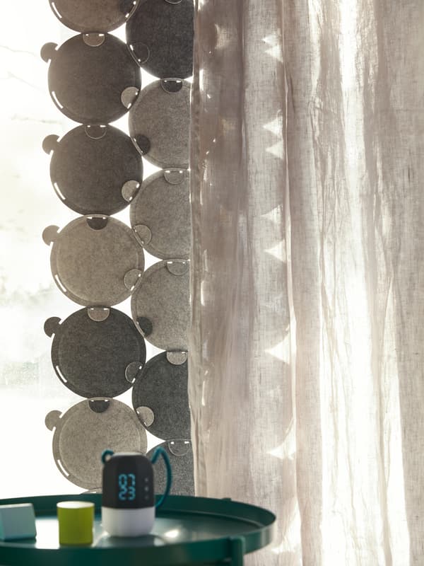 Light streams through a window, partly covered by ODDLAUG sound absorbing panels and an opaque curtain.
