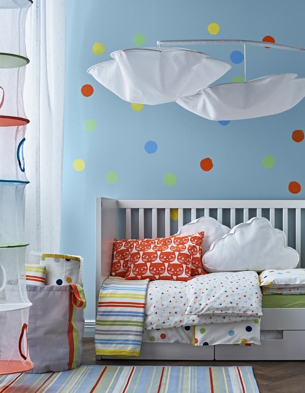 Linge de lit, tapis, et pastilles peintes au mur, le tout en couleurs vives, passeront facilement la transition de chambre de bébé à chambre d’enfant.