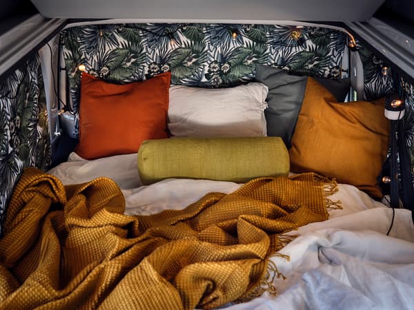 L'intérieur du van rempli de coussins et de couvertures colorées.