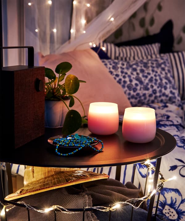 Lit en arrière-plan, table d’appoint ronde, haut-parleur Bluetooth® ENEBY et bougies parfumées