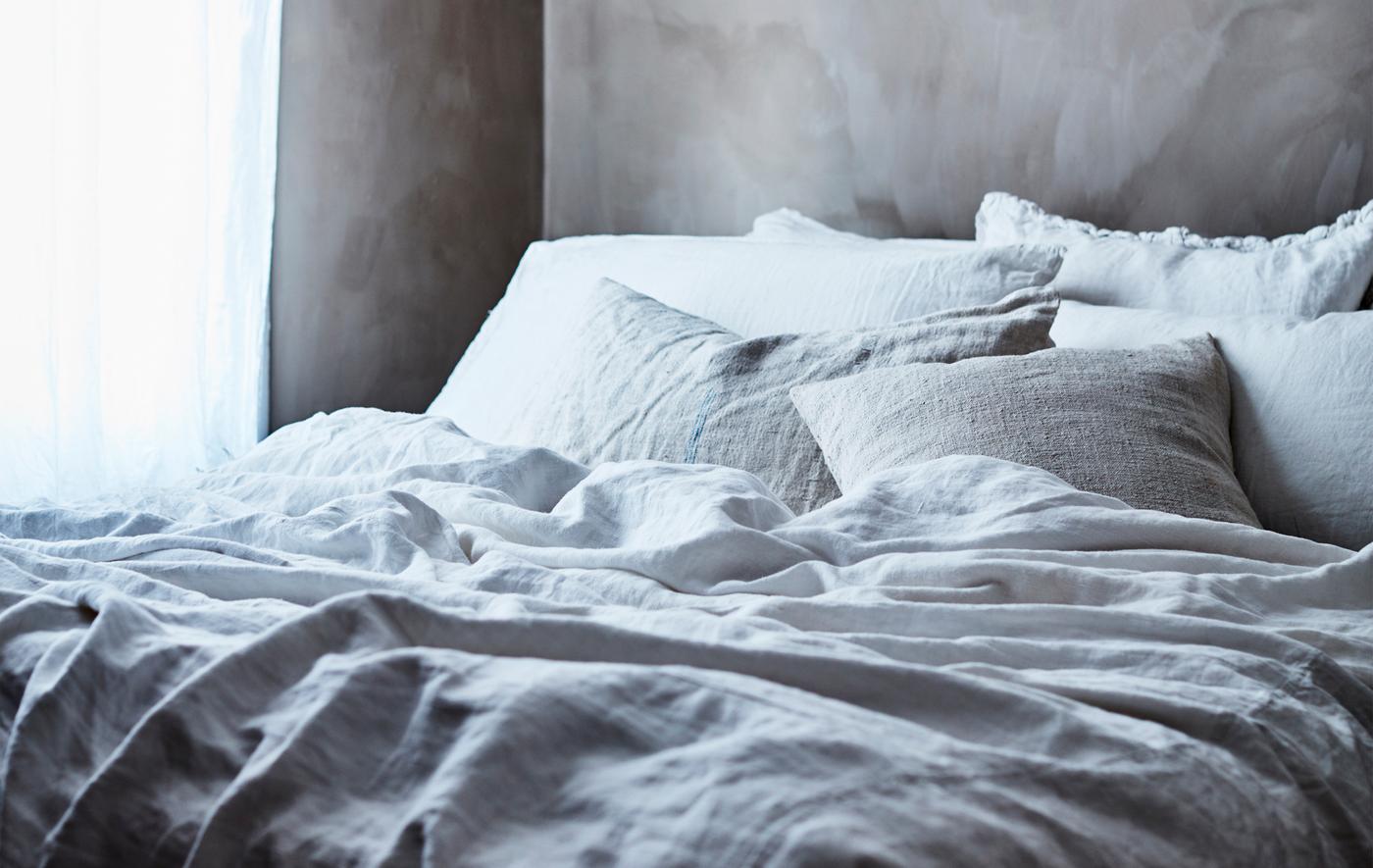 Lit garni d'un linge de lit gris et blanc.
