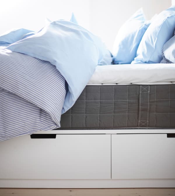 Lit vu de côté, avec rangements sous le lit et matelas.