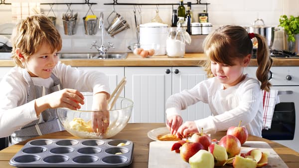 Little boy and girl preparing muffins in the kitchen.