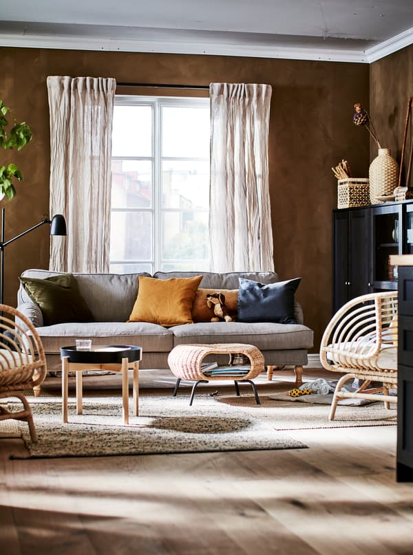 Living room in an earthy-shades colour scheme with decorations, storage, BUSKBO armchairs, a sofa, side table and footstool.