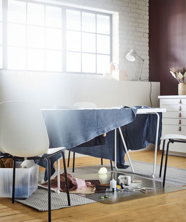 Living room table with a length of fabric draping over the sides, framing an improvised workplace for drawing or the like.