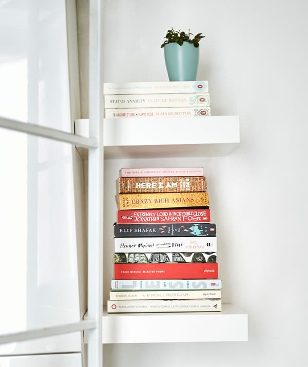 Livres empilés sur des tablettes blanches.