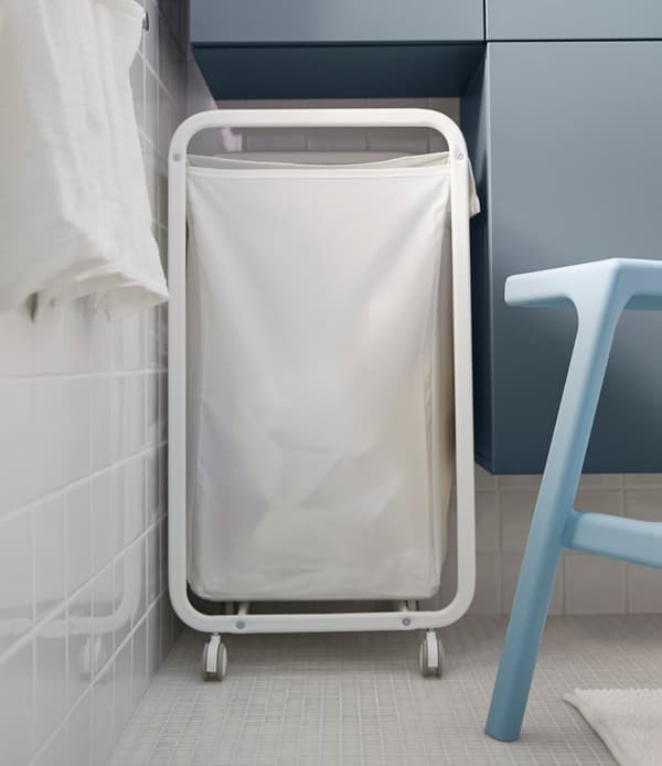 Looking for big storage in a small bathroom? One tip is to design a space in between wall cabinets for other things  like this laundry basket.