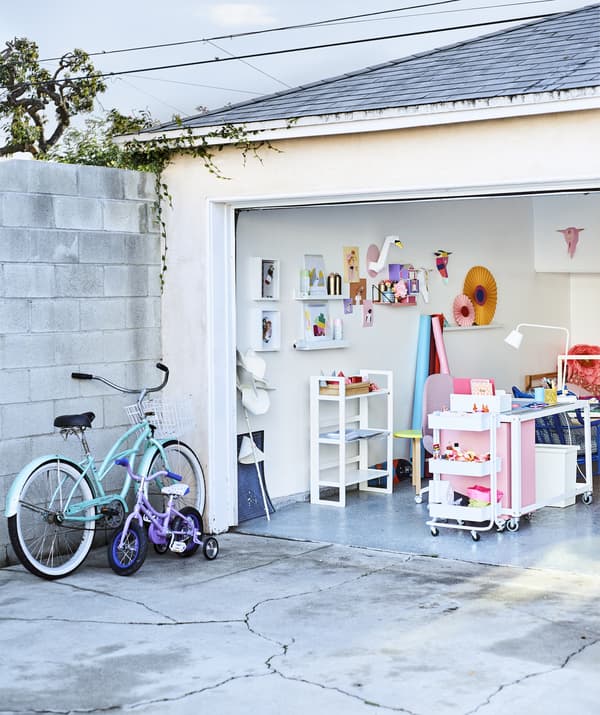 Looking into a colourful home office in a garage from the concrete driveway.