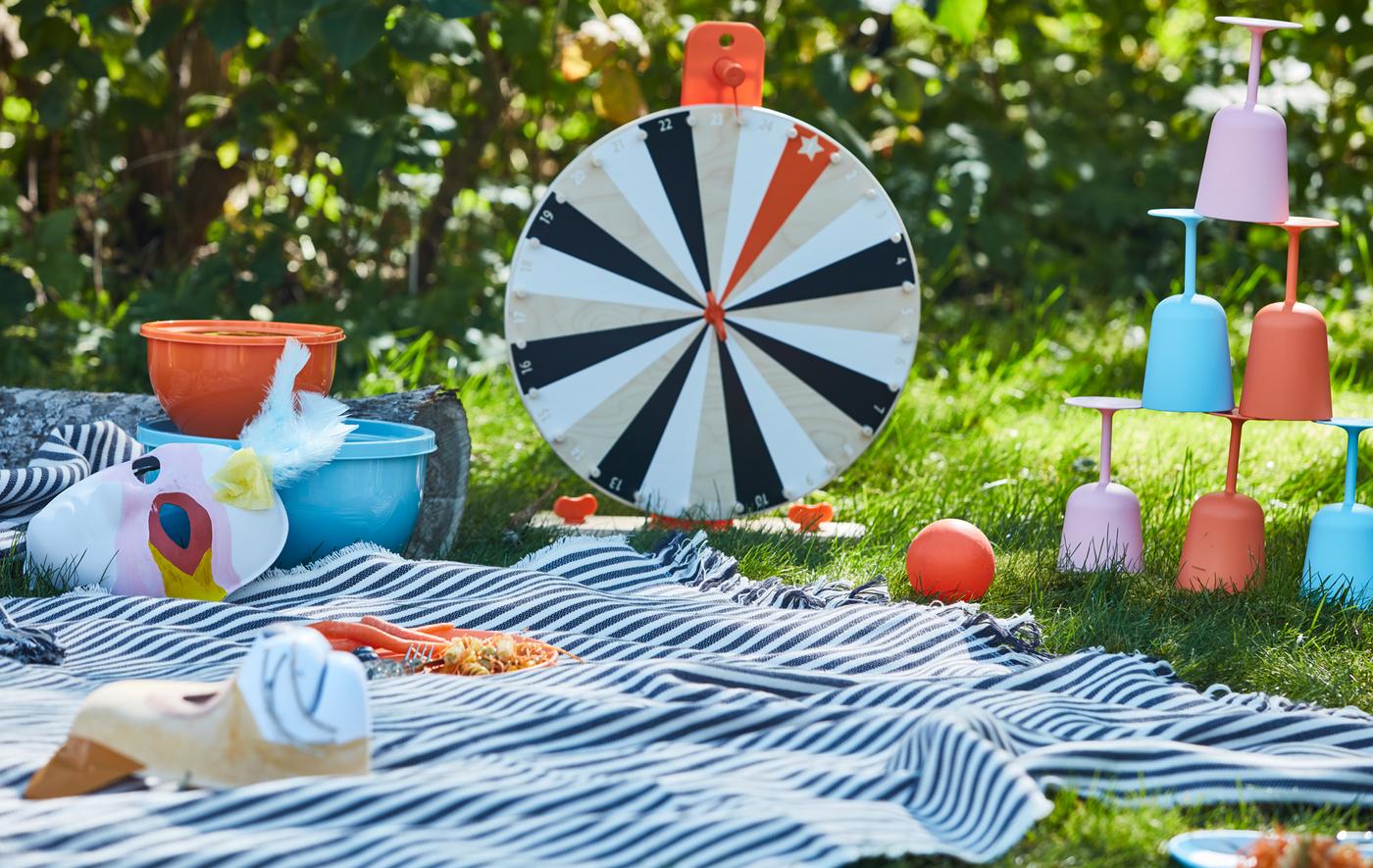 피크닉담요 위에 원목 소재의 LUSTIGT/루스틱트 행운게임과 깨질 염려 없는 식기세트가 놓여져 있어요.