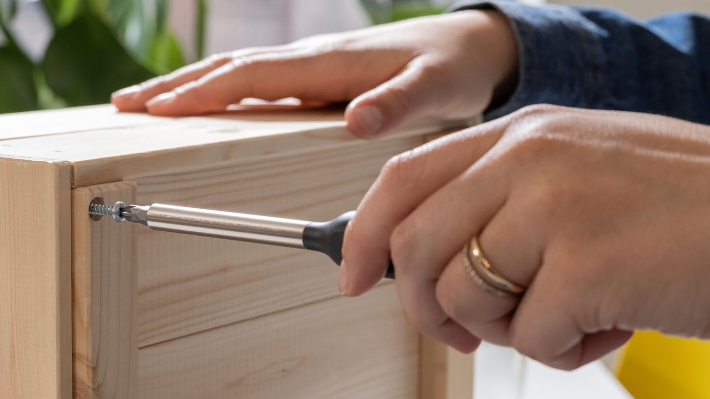 Main plaçant une vis pour réparer une armoire.