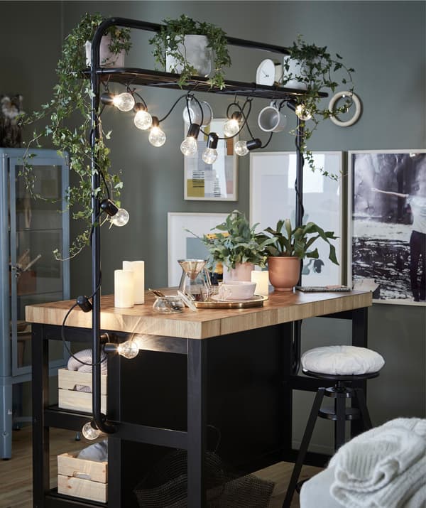 Make your kitchen island a manifest, miniature retreat filled with objects that serve your well-being, here with mood lighting and hanging greenery.