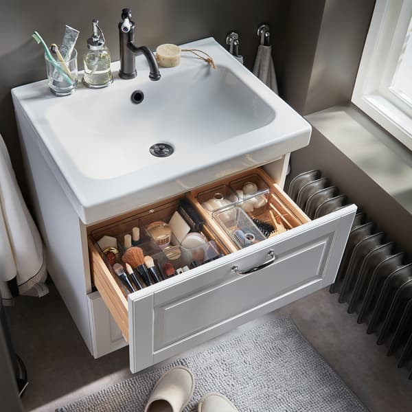 Makeup, hair tools and beauty tools are nicely organised in smoke-coloured see-through boxes that are in a wash stand drawer.