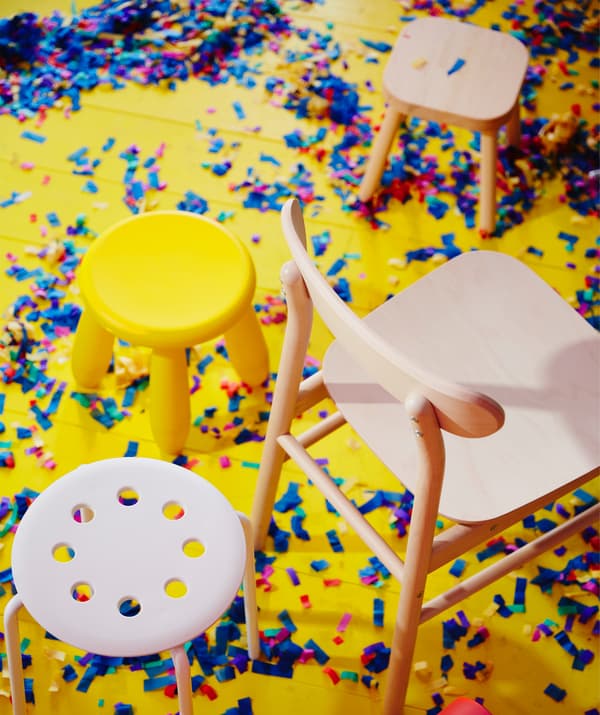 MAMMUT and MARIUS plastic chairs and RÖNNINGE chair in solid birch, standing on the floor during a party.MAMMUT and MARIUS plastic chairs and RÖNNINGE chair in birch, against a bright yellow floor scattered with confetti.