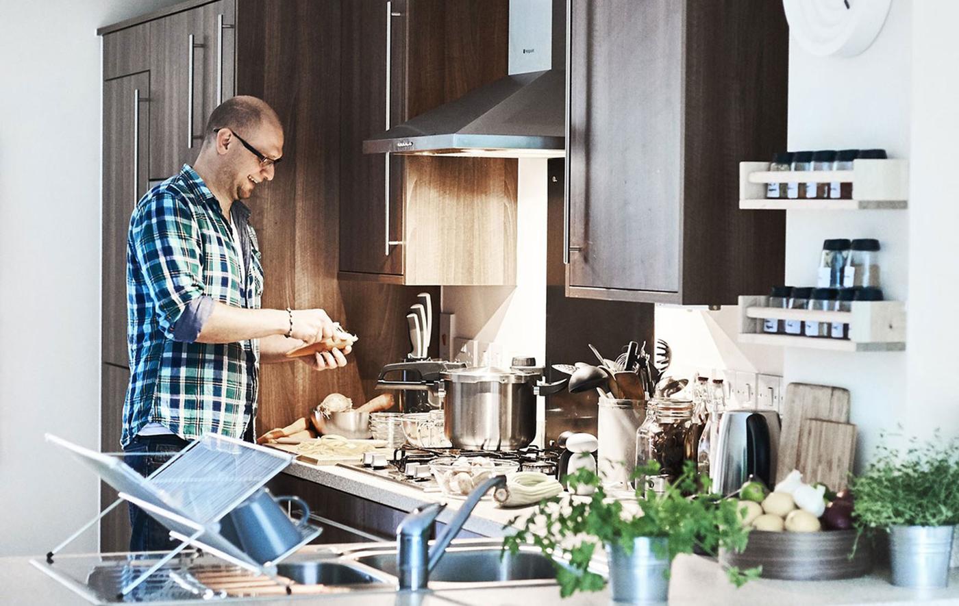 Man in blue shirt standing by the stove in his kitchen.