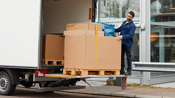 Man loading large cardboard IKEA boxes from a pallet onto a delivery truck