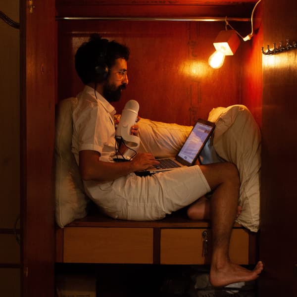 Man recording a podcast in his home made recording environment – his wardrobe, using a duvet to adjust the acoustics.