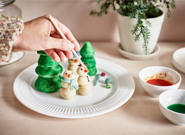 Marzipan figures being painted with food colouring.