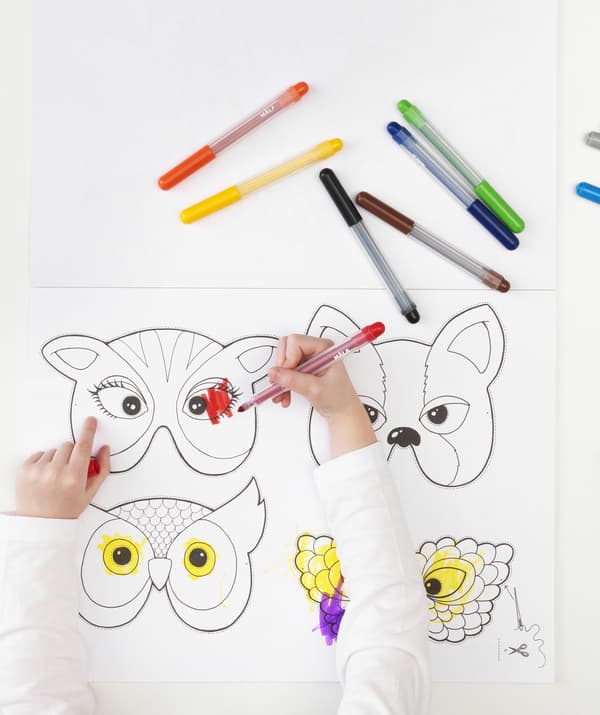 Masques tirés du livre d’activités IKEA et un enfant qui colorie.