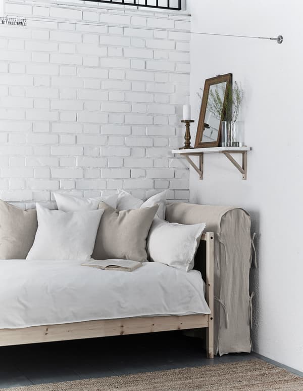 Matelas plié recouvert d'une housse faite maison et rangé entre le lit et le mur.