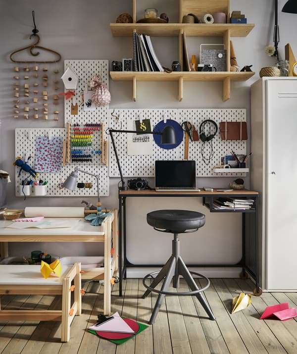 Materiali artistici su una scrivania per bambini accanto a una scrivania per adulti con uno sgabello e un pannello portaoggetti - IKEA