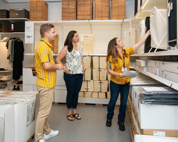 Megan and two uniformed IKEA employees at an IKEA store.