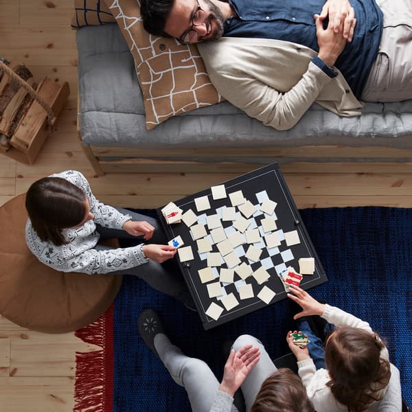 Membres d’une famille assis et couchés autour d’un jeu de société joué sur une table basse.