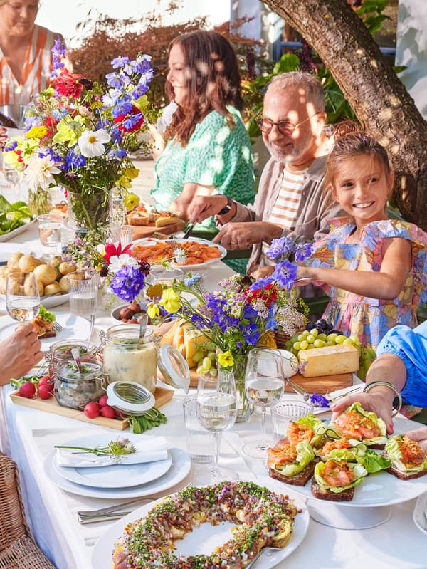 Midsommarová hostina s vázami květin, sledi, lososem a bramborami.