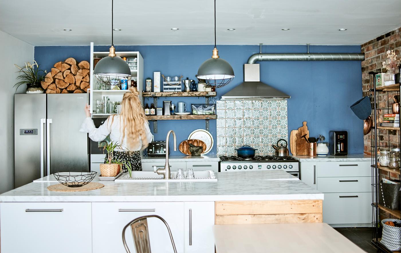 Minimalistisch offener Wohnraum und Küche mit blauer Wand