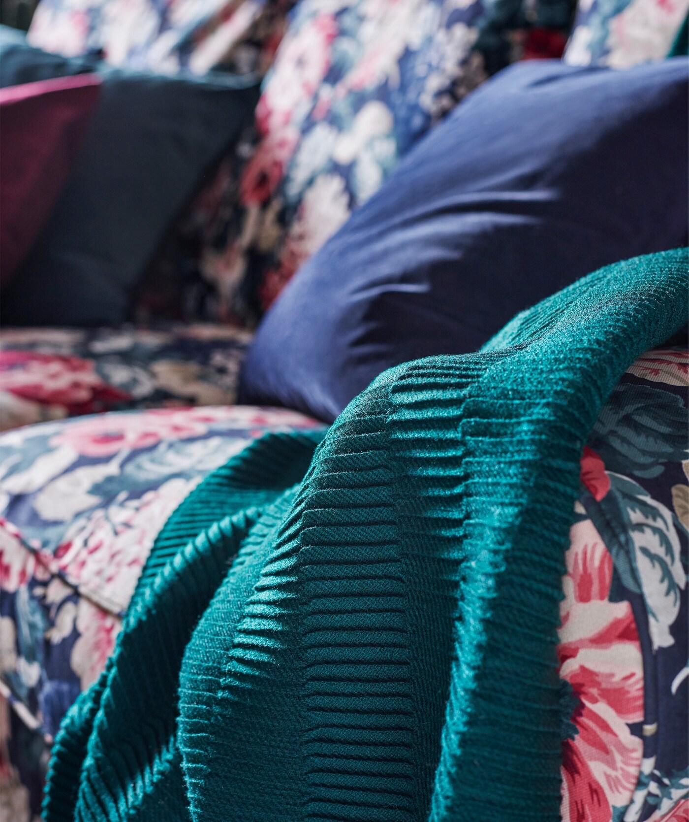 Mit dunklen, warmen Farben wirkt ein Wohnzimmer tagsüber einladend und gemütlich, lässt sich aber bei Nacht schnell in einen geheimnisvollen, gruseligen Ort verwandeln. Hier ist u. a. VÄGMÅLLA Plaid in Grün zu sehen.