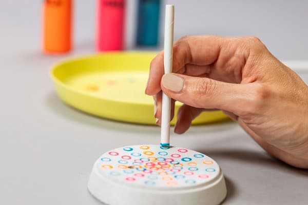 Mit Hilfe eines Trinkhalmes und MÅLA Farben werden bunte Kreise auf den Korkuntersetzer gestempelt. 