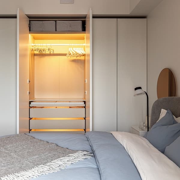 Modern bedroom wardrobe with open doors, interior lighting, and storage boxes.