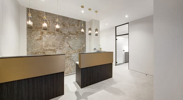 Modern dental clinic reception area with elegant pendant lighting, marble accent wall, and minimalist front desks.