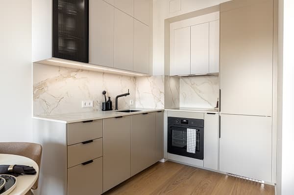 Modern kitchen design with built-in oven, marble backsplash, and beige cabinets.